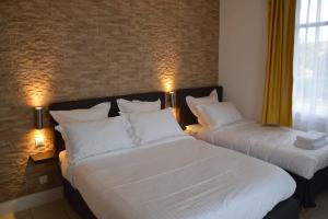 two beds in a hotel room with white sheets at Hotel Castellamar in Sainte-Maxime