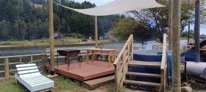 a wooden deck with a table and a tub at Pieza con vista Espacio Rio Chovellen in De Cauquenes