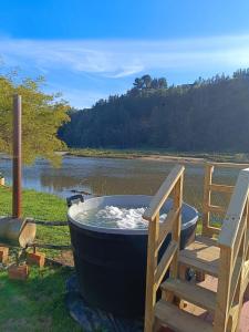a large bath tub sitting next to a wooden deck at Pieza con vista Espacio Rio Chovellen in De Cauquenes +4 photos