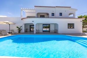 a villa with a swimming pool in front of a house at Vivenda Vilhegas in Albufeira