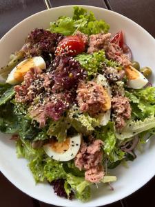 Ein Salat mit Eiern, Salatblättern und Tomaten auf einem weißen Teller in der Unterkunft Каньон in Grushevtsy