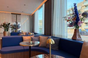 a living room with a blue couch and a large window at TRYP Badhotel The Hague Scheveningen BRAND NEW in Scheveningen