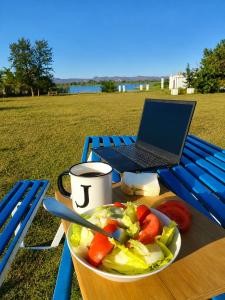 a plate of salad and a laptop on a blue bench at Whispering Woods in Kafue