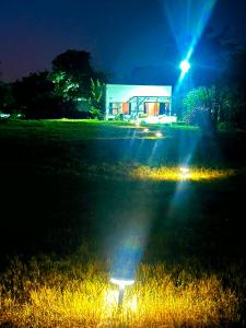 a building with lights in a field at night at Whispering Woods in Kafue