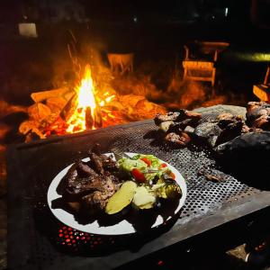 a plate of food in front of a fire at Whispering Woods in Kafue