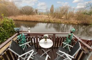 einen Tisch und Stühle auf einer Terrasse neben einem Fluss in der Unterkunft Isleham River Lodge in Isleham