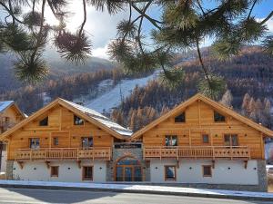 a log cabin with a snow covered mountain in the background at Izoard in Saint-Chaffrey