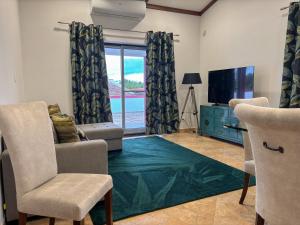 a living room with a television and a couch and chairs at Chalé d'Angra Guest House in Angra do Heroísmo