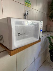 a microwave sitting on a shelf on a wall at Casa de Gente Feliz in Cuiabá