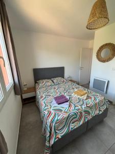 a bedroom with a bed with a colorful comforter at Appartement T2 moderne - Résidence Lecci - Piscines & proche Mer in Lecci