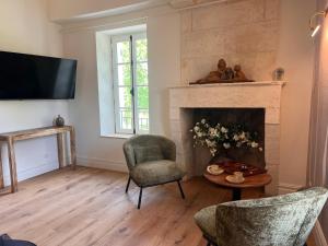 a living room with a fireplace and two chairs at Hôtel Le Groom in Laprade