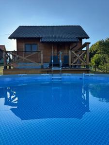 a log cabin with a pool in front of a house at Brvnara Beli in Gornji Milanovac