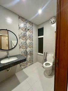 a bathroom with a toilet and a sink and a mirror at Premium Pavilion in Islamabad