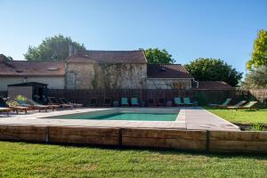 a swimming pool in a yard with chairs and a fence at Hôtel Le Groom in Laprade