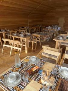 a room with wooden tables and chairs with plates and bowls at Kel-Suu Manap in Kol-Suu