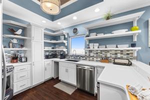 a kitchen with white cabinets and blue walls at The Alexander in Rosemary Beach