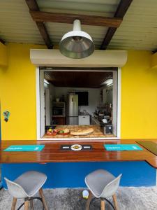 a kitchen with yellow walls and two chairs and a table at Chambre d'hôtes Jungle Hostel in Le Morne Rouge