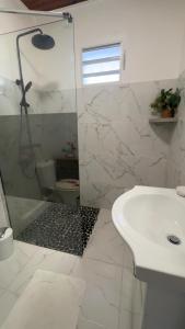 a white bathroom with a shower and a sink at Kéra Lodge in Rivière-Pilote