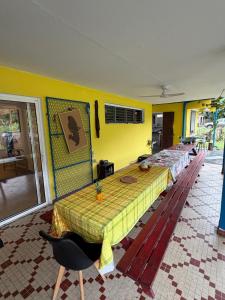 a room with a yellow wall with a row of tables at Chambre d'hôtes Jungle Hostel in Le Morne Rouge