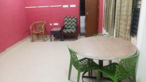 a table and chairs in a room with a pink wall at CHIDAMBARAM Bala Residency in Chidambaram +1 photo