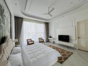 a white bedroom with a large bed and a tv at Sukoon Luxury Stay in Amritsar