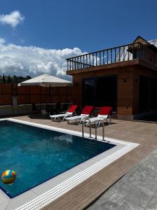 a swimming pool with chairs and a house at Bungavilla in Atakum