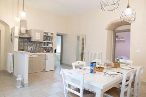 a kitchen and dining room with a white table and chairs at Dimora dei Grifi in Ascoli Satriano