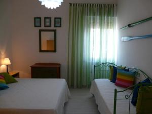 een slaapkamer met 2 bedden en een raam met groene gordijnen bij Appartamento Tino in Castiglione della Pescaia