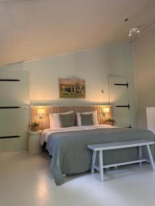 a bedroom with a large bed and a bench at Zen appartement in Vries