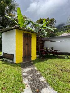a yellow and white house with a bench next to it at Chambre d'hôtes Jungle Hostel in Le Morne Rouge
