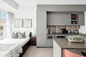 a white bedroom with a bed and a kitchen at Entertainment District Gem Walk to CN Tower in Toronto