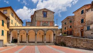 an old building with a tower and a stone wall at L'Angolo dei Sogni in Lucignano