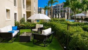 a patio with chairs and a table and an umbrella at Chalet with garden-marassi marina 2- Pool View in El Alamein