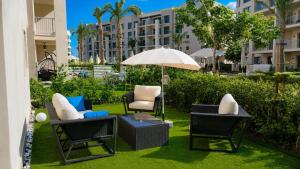 a patio with chairs and a table with an umbrella at Chalet with garden-marassi marina 2- Pool View in El Alamein