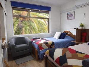 a bedroom with two beds and a chair and a window at Hostal Rucatremo in Curicó