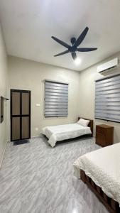 a bedroom with two beds and a ceiling fan at Baba Homestay in Macang