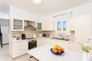a kitchen with white cabinets and a bowl of fruit on a table at Amphitrite Villa in Gennadi