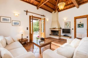 a living room with white furniture and a fireplace at Villa Ioanna in Skopelos Town