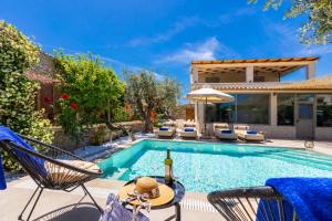 a swimming pool with chairs and a house at Villa Ammos in Afantou
