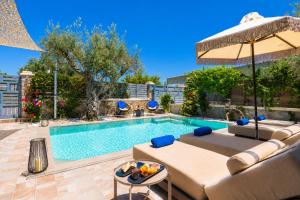 a swimming pool with a couch and an umbrella at Villa Ammos in Afantou