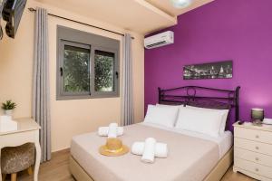 a bedroom with a purple wall and a bed with towels at Villa Ammos in Afantou +14 photos