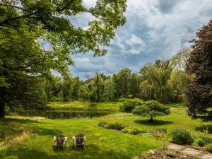 two chairs sitting in the grass near a pond at The Whistling Oak - Pristine Pond Tranquility in Craryville