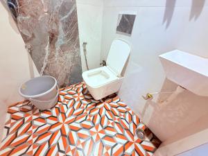 a bathroom with a toilet and a mosaic floor at Hotel Iris Inn - Near Lodha Palava, Dombivali in Dombivli +23 photos