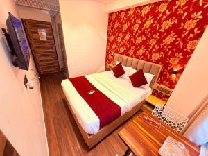 a small bedroom with a bed with a red wall at Hotel Iris Inn - Near Lodha Palava, Dombivali in Dombivli