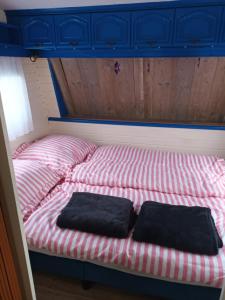 a bed with two black pillows sitting on it at CHILLY WILLY Retro Caravan & Hot Tub in Jablonov nad Turnou