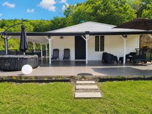 a white house with a patio with an umbrella at Villa Pauline in Les Abymes
