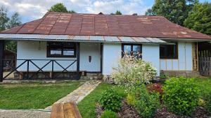 a white house with a rusty tin roof at Ya VDOMA in Kozmacz