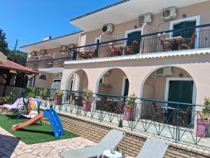 a house with chairs and a playground in front of it at Filoxenia Studios and Mermaid Pool in Paleokastritsa