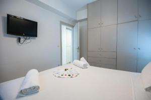 a white bedroom with a white bed with a tv on it at Ermira in Agios Nikolaos