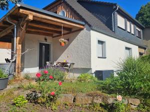 a house with a patio with a table and flowers at Ferienwohnungen Familie Gottfried in Schirgiswalde